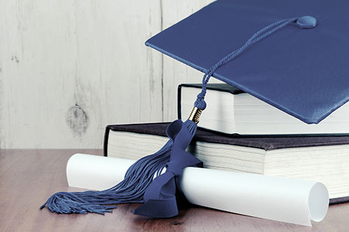 blue graduation cap with books nad a diploma