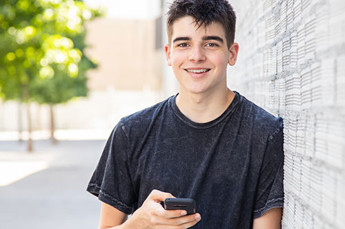 Smiling male teenager holding a cell phone